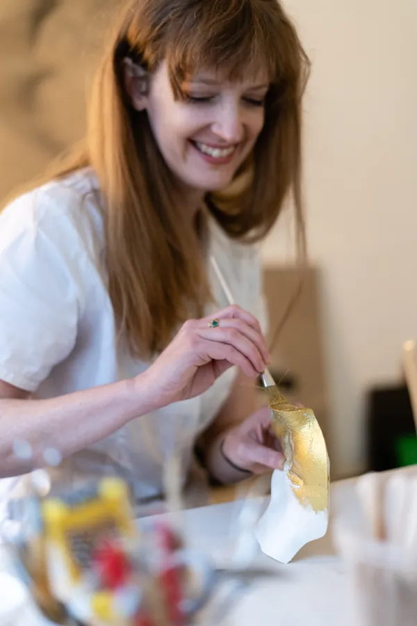 Brooke applying gold leaf to a plaster cast with a fine brush
