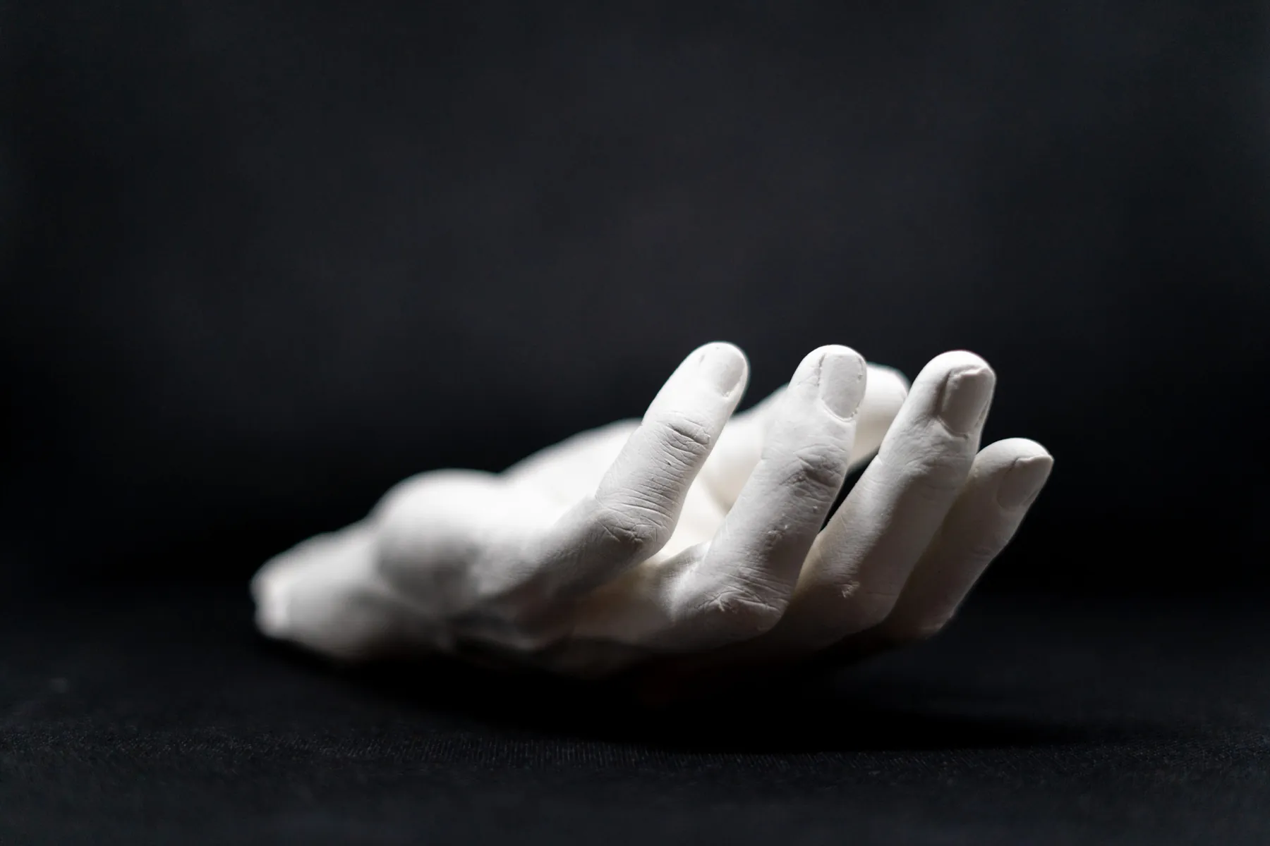 Plaster cast of a hand resting palm down on black