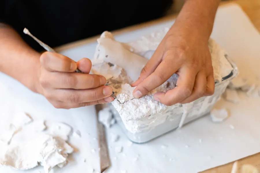 Workshop participant carefully freeing a plaster cast from its mould