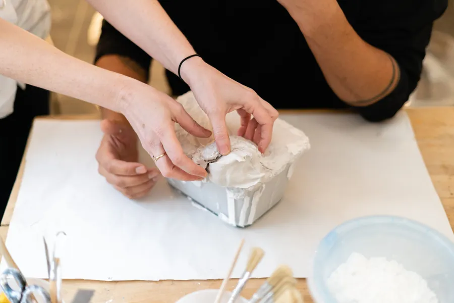 Hands working wet plaster into a mould